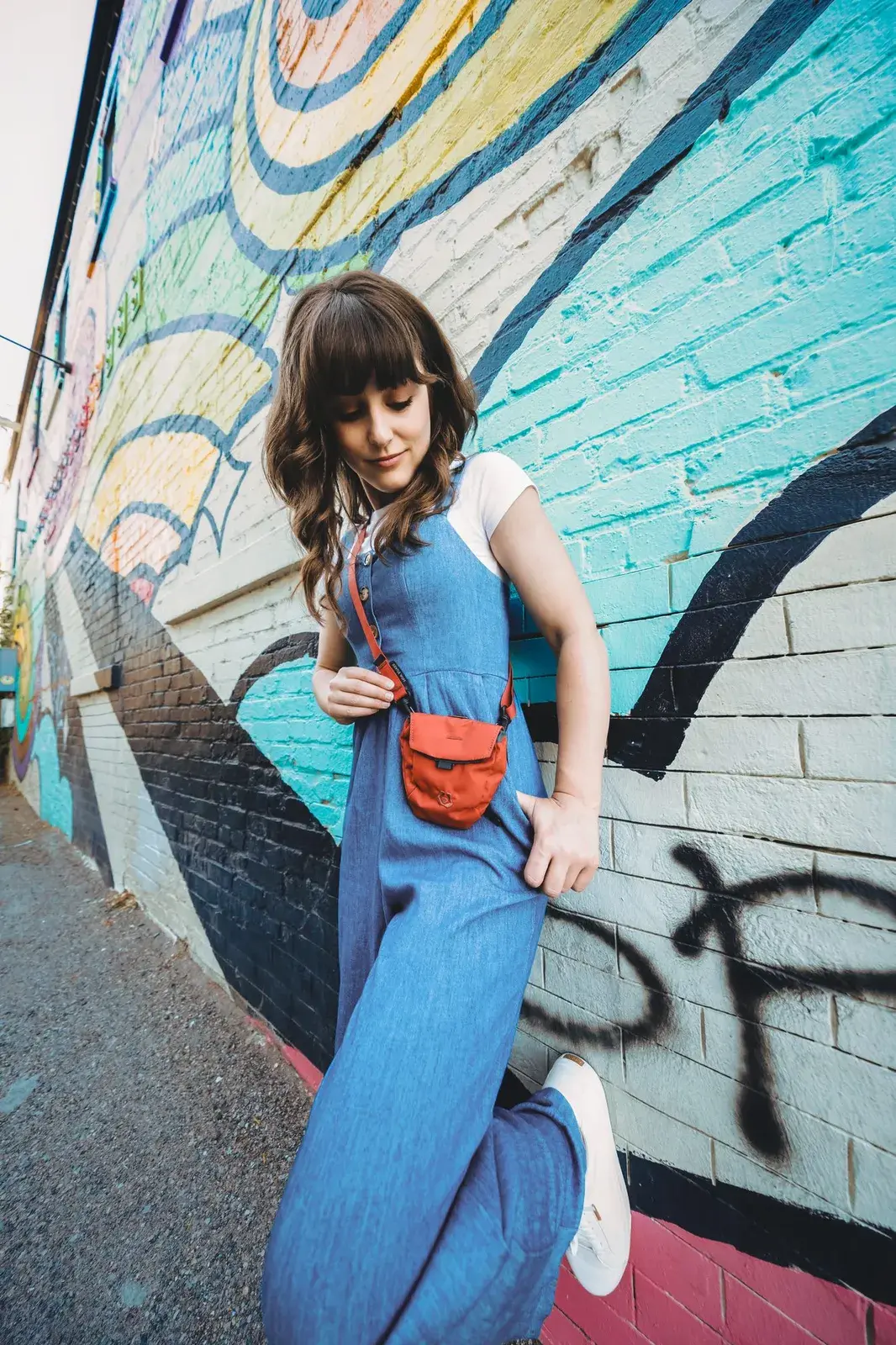 Woman wearing a Canyon Snack Sack on its strap in front of a painted mural
