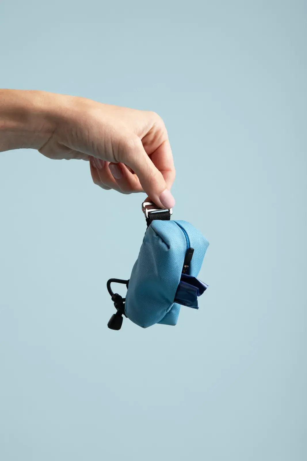 Hand holding the Poo Pouch with a bag ready to dispense